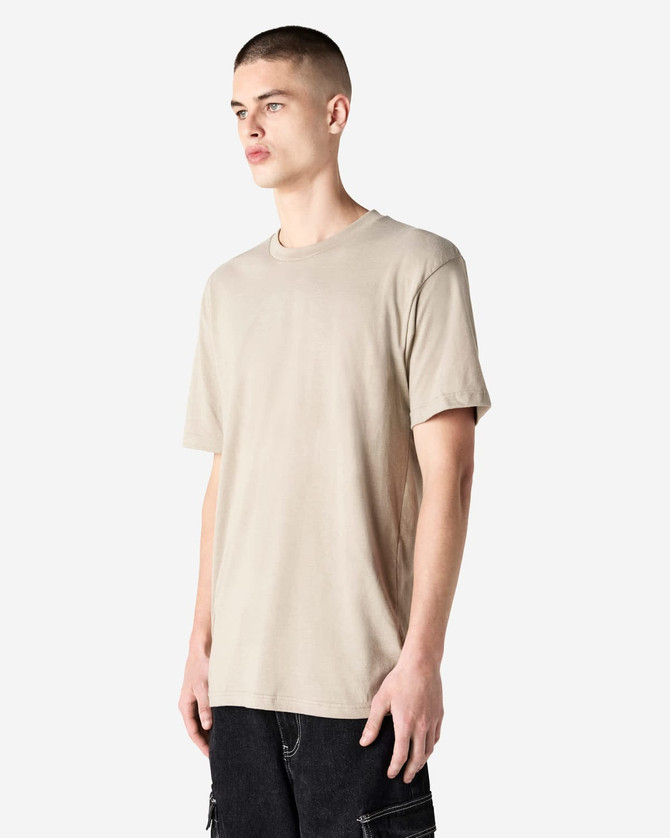 A unisex beige CVC short sleeve T-shirt displayed on a model, featuring a logo.