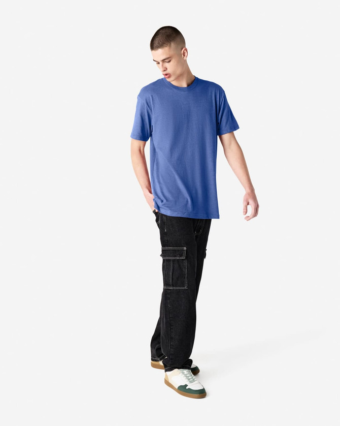 A unisex CVC short sleeve T-shirt in blue, paired with black cargo pants and casual footwear.