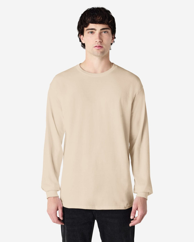 A long sleeve t-shirt in beige worn by a model, featuring a relaxed fit and a branding logo.
