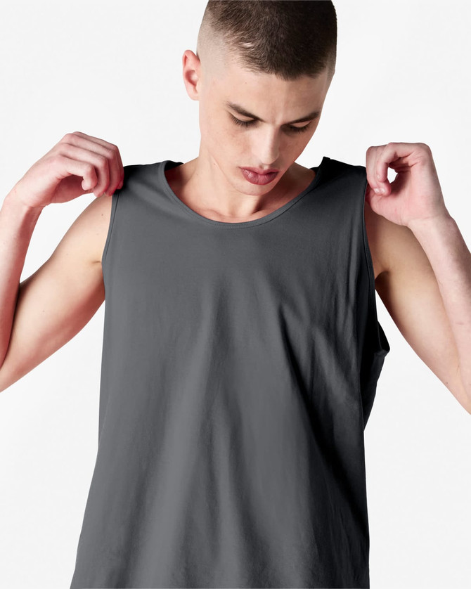 A unisex fine jersey tank in grey, featuring wide armholes and a simple design. The model is adjusting the tank.