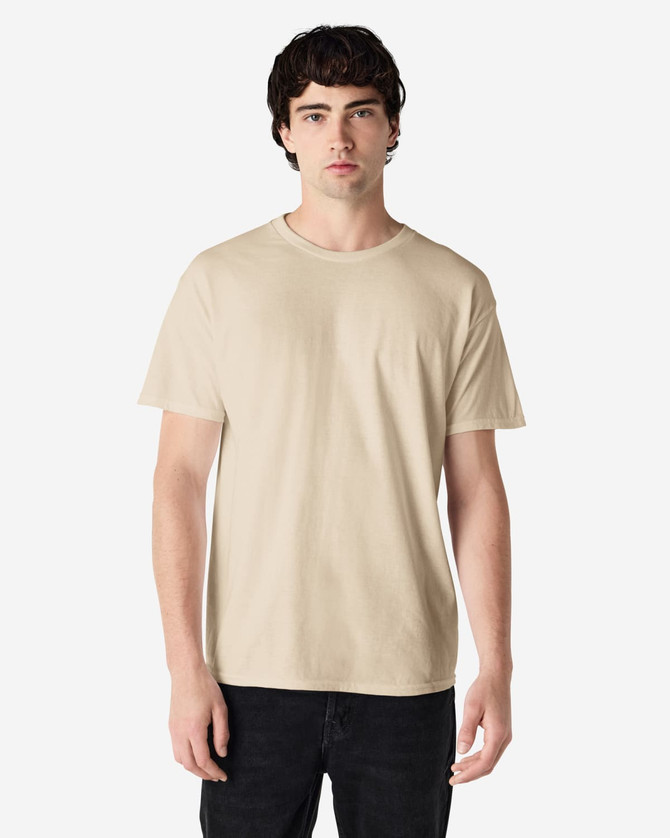 A light beige adult t-shirt in a casual style, featuring a crew neck and short sleeves. It has a branding logo on the tag.