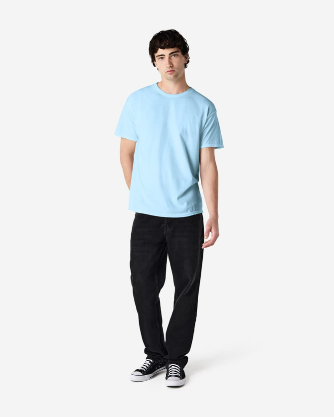 A light blue Gildan Heavy Cotton adult t-shirt displayed on a male model wearing black pants and sneakers.