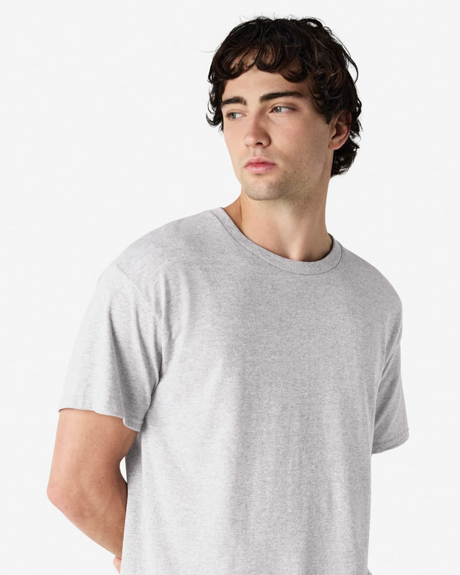 A grey Gildan Heavy Cotton Adult T-Shirt displayed on a model, featuring a round neckline and short sleeves.