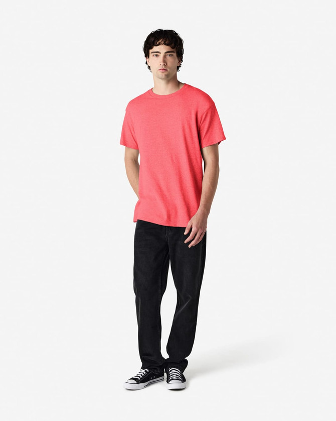 A coral Gildan Heavy Cotton Adult T-Shirt worn by a model, paired with black pants and casual sneakers.