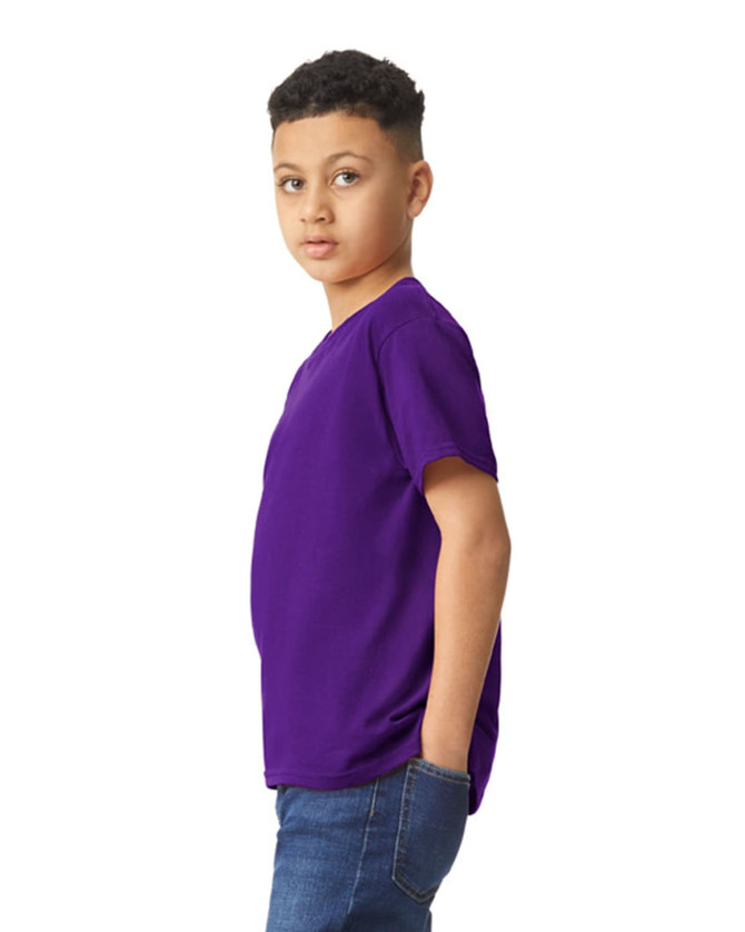 A young model wearing a purple Gildan Heavy Cotton Youth T-Shirt, posing sideways with hands in pockets.