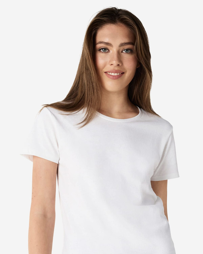 A white Gildan Heavy Cotton Ladies' T-Shirt displayed on a model, featuring a simple design and a logo.