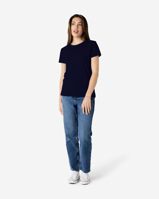 A model wearing a navy blue Gildan Heavy Cotton Ladies' T-Shirt paired with blue jeans and white sneakers.