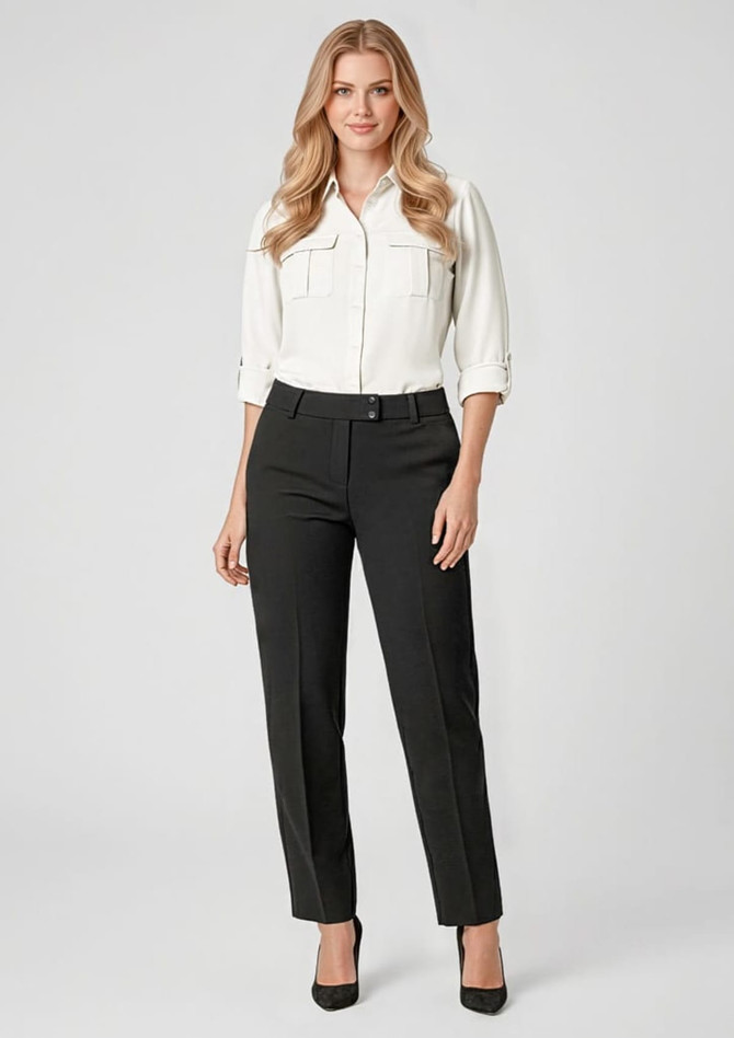 A woman wears black slacks paired with a white button-up shirt and heels, posing against a neutral background.