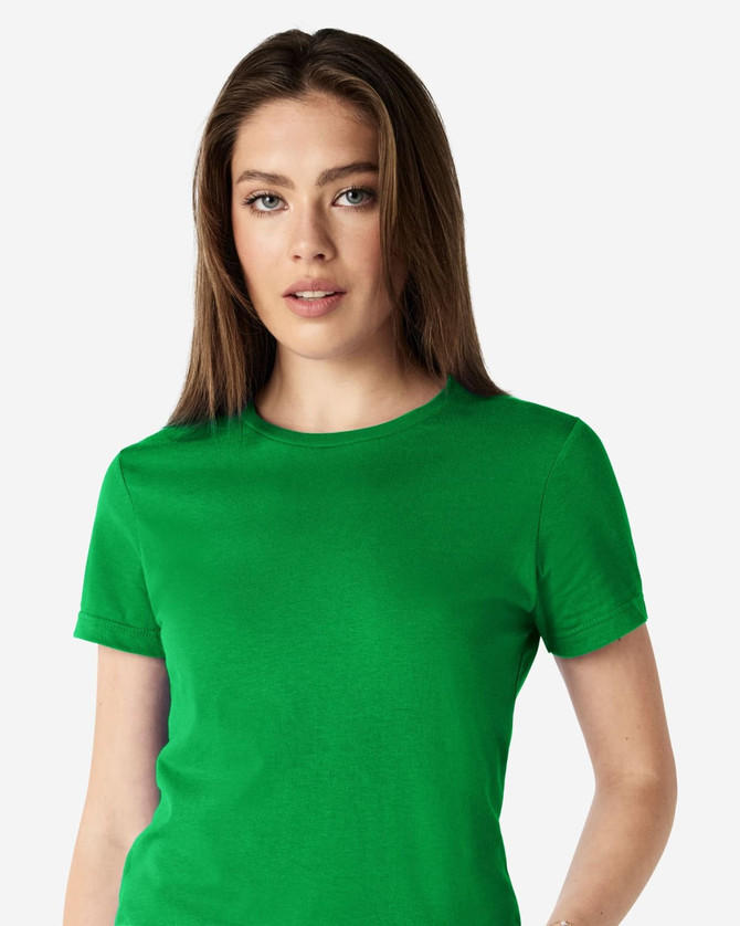 A green Gildan Softstyle ladies' t-shirt displayed on a model with long hair. The shirt has a logo on it.