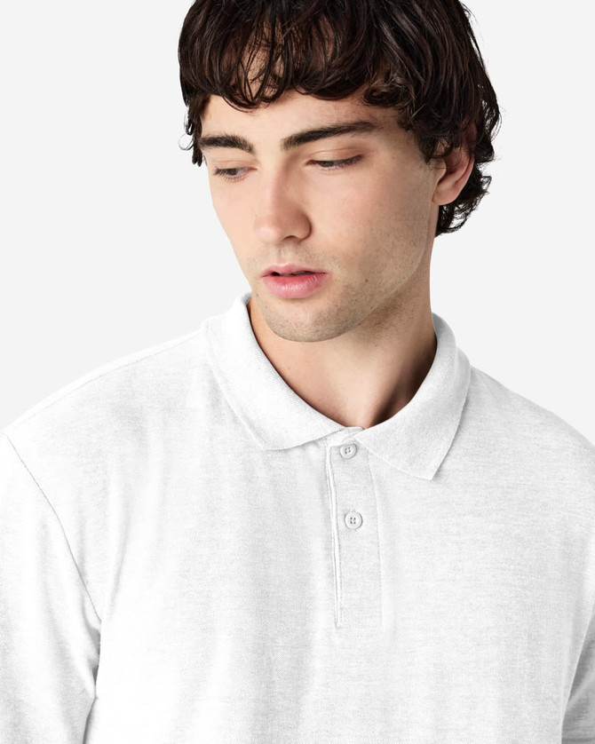 A white Gildan Softstyle adult double pique polo shirt on a model, featuring a collar and three buttons.