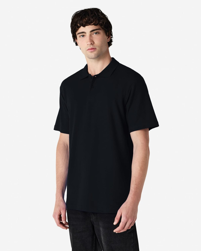 A model wearing a black Gildan Softstyle Adult Double Pique Polo, featuring a classic polo collar and short sleeves.