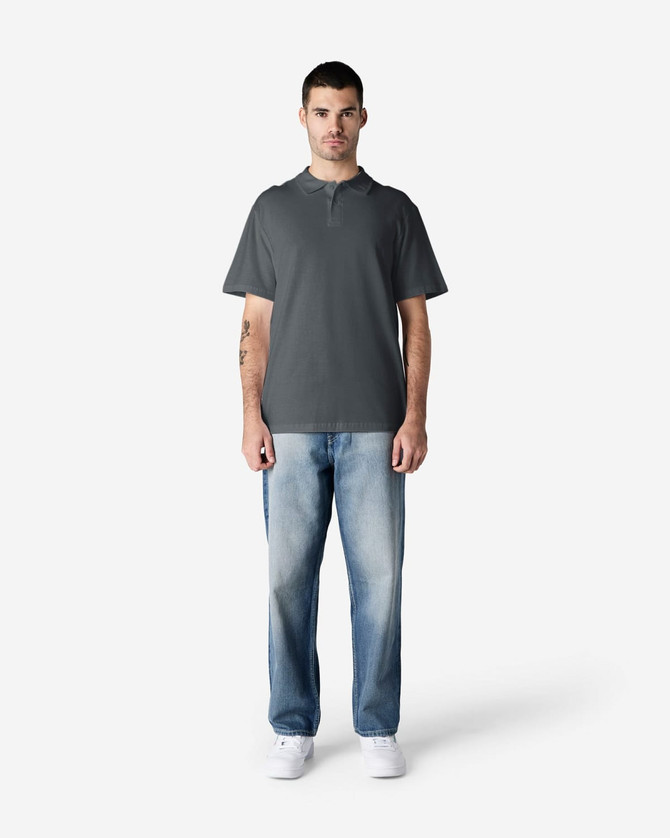 A grey Gildan Softstyle Adult Double Pique Polo is worn by a model, paired with light blue jeans. The polo features a logo.