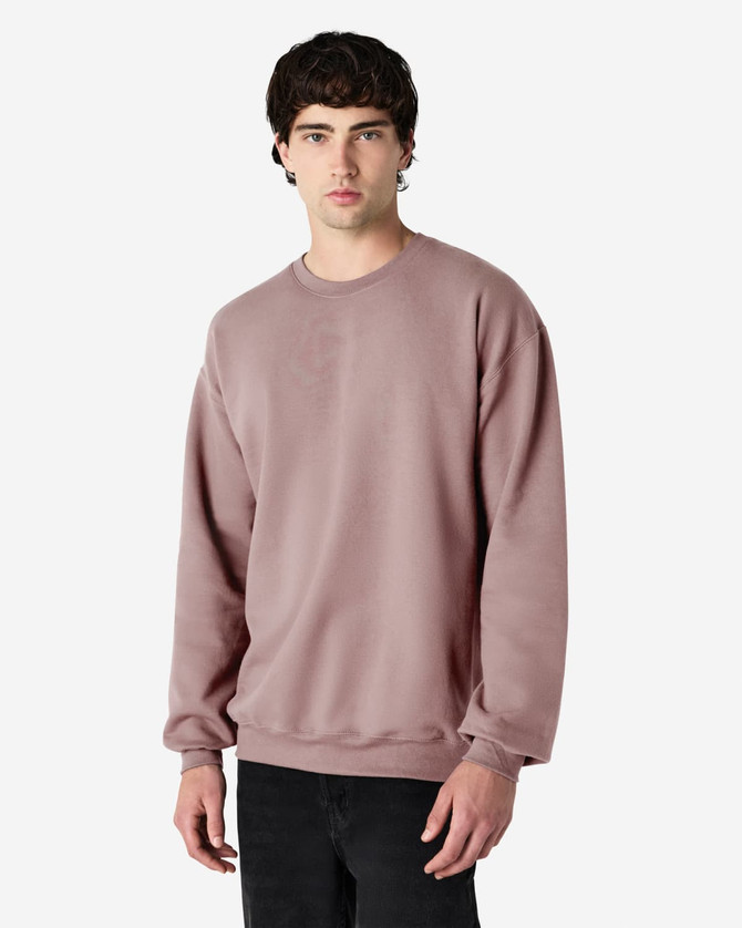 A softstyle adult sweatshirt in a mauve colour, featuring long sleeves and a relaxed fit. It has a logo.