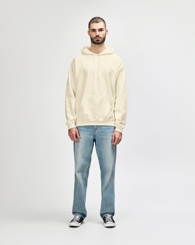 A hooded sweatshirt in cream, featuring a front pocket and a drawstring hood, modelled by a smiling man.
