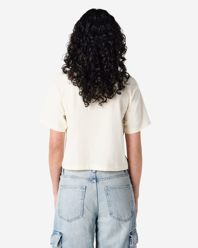 A beige women's boxy t-shirt with short sleeves, viewed from the back, featuring a logo. Casual style, perfect for layering.