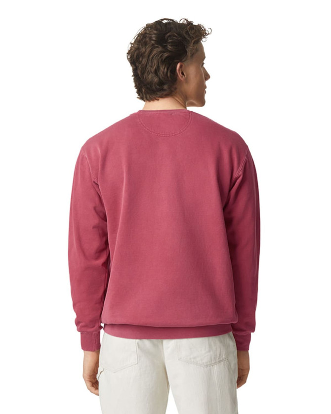 A crewneck sweatshirt in a deep pink shade, featuring a simple design and ribbed cuffs at the wrists. 