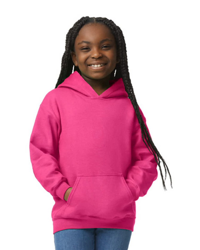 A girl wearing a pink Gildan Heavy Blend youth hooded sweatshirt, featuring a front pocket and hood.