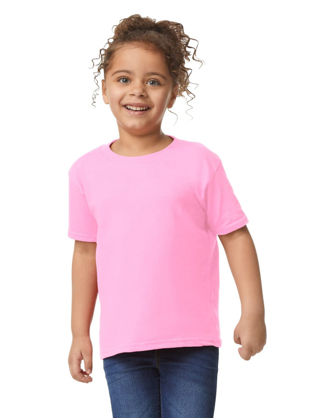A pink toddler t-shirt with short sleeves, featuring a branding logo, worn by a smiling child.
