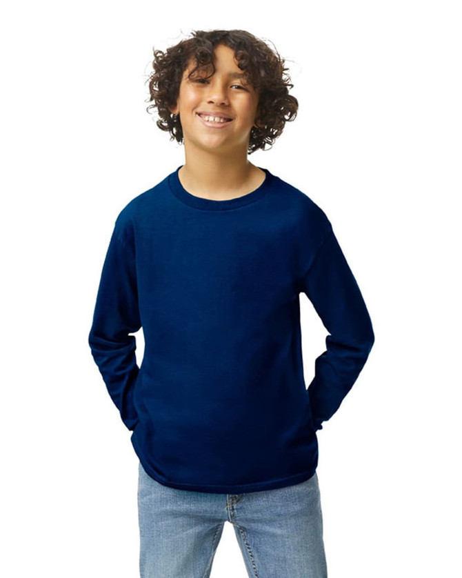 A youth long sleeve T-shirt in navy blue with a relaxed fit and logo. The model is smiling and wearing denim jeans.