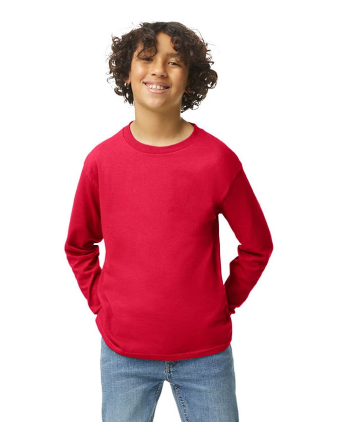 A youthful model wearing a bright red Gildan Heavy Cotton long sleeve t-shirt, paired with blue jeans.