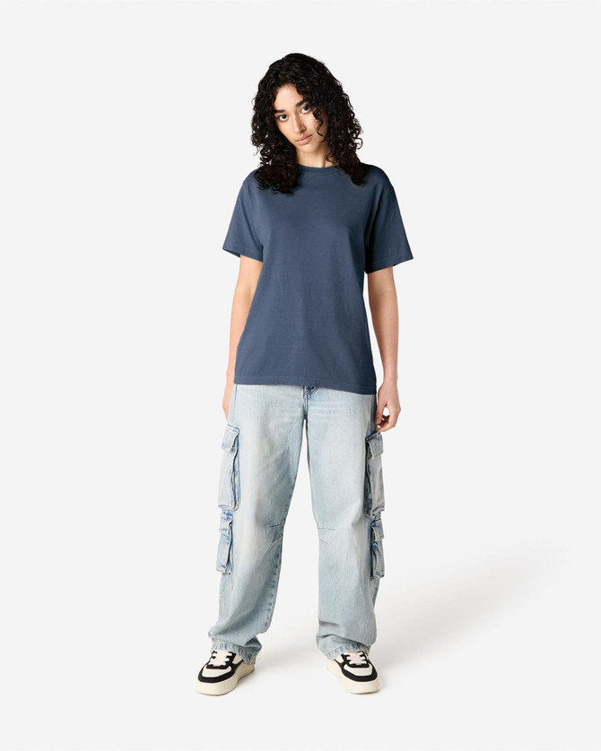 A navy unisex t-shirt made of heavyweight cotton, modelled by a person wearing light cargo jeans.