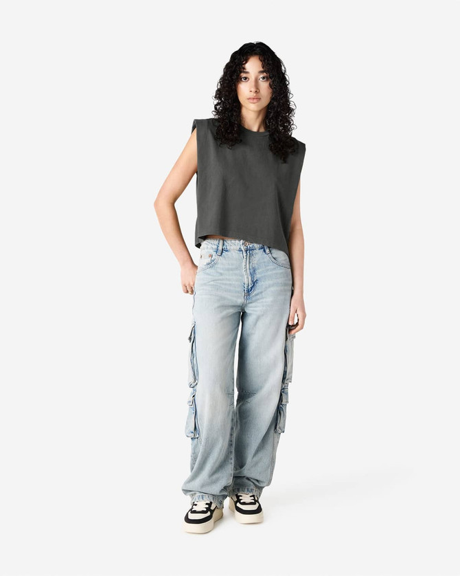 A grey women's muscle t-shirt paired with light blue baggy jeans and black and white sneakers.