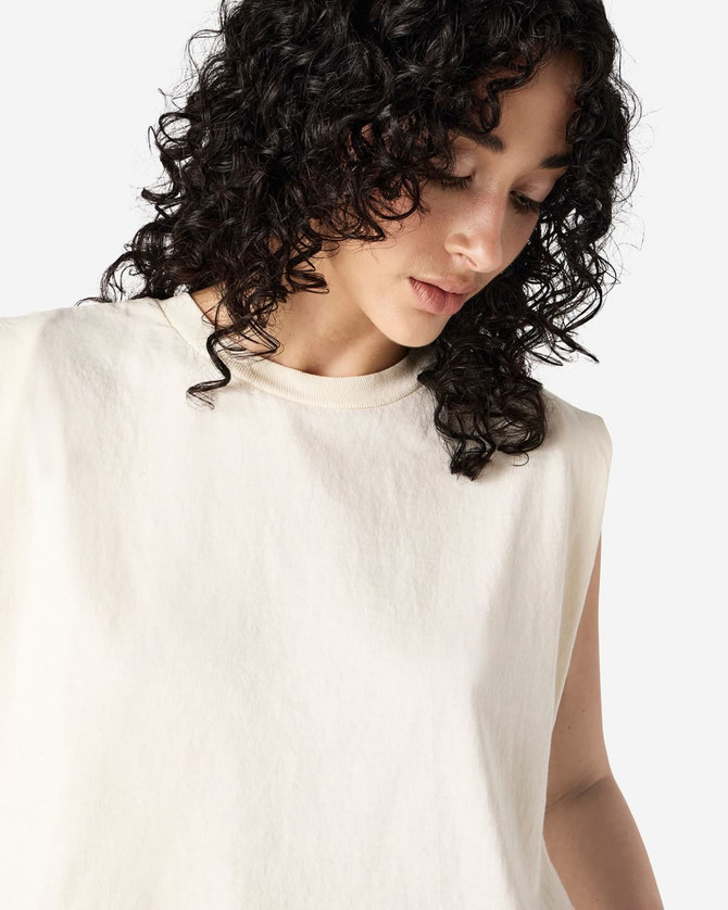 A cream-coloured muscle T-shirt with a relaxed fit and no sleeves, featuring a small logo.