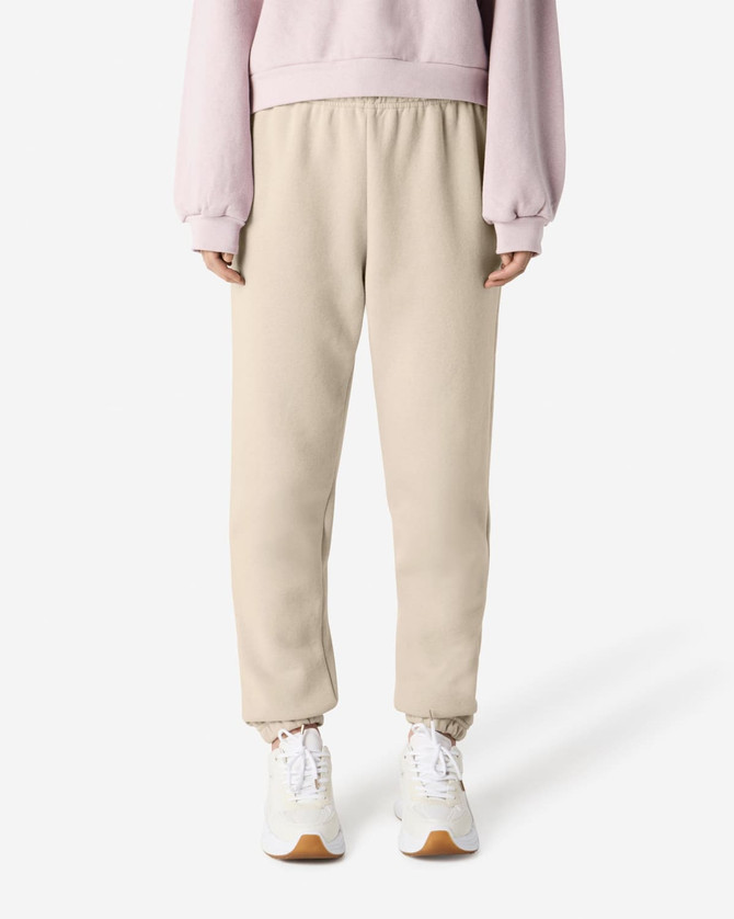 Unisex sweatpants in beige with an elastic waistband and cuffed ankles, paired with a light pink sweat top.