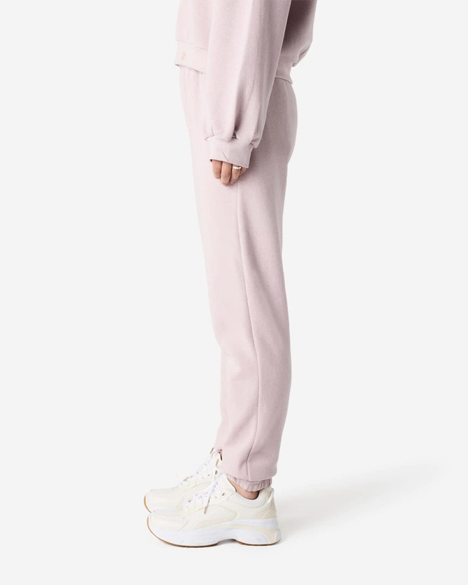 Unisex sweatpants in soft pink, featuring a snug fit and side pockets. Includes a visible logo detail.