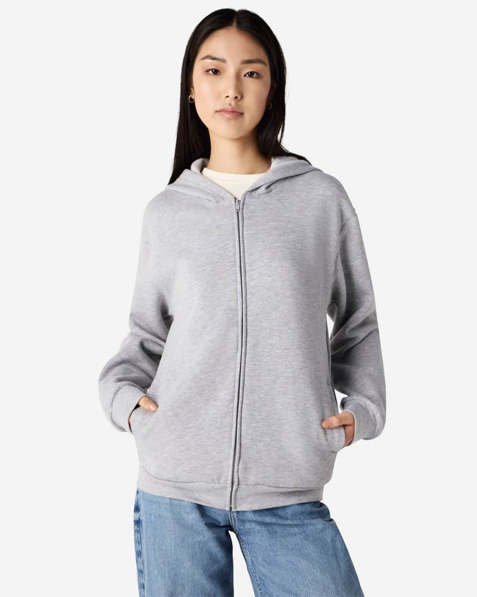 A unisex full zip hooded sweatshirt in heather grey with a hood and pockets. The model stands with hands in pockets.