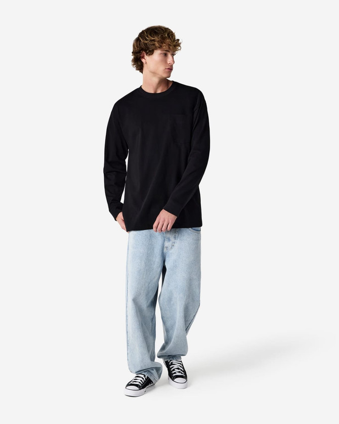 A black Super Heavyweight T-Shirt paired with loose blue jeans and black sneakers, displayed on a model.