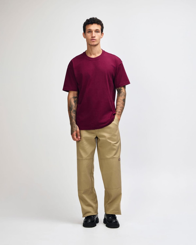 A model wearing a maroon heavyweight T-shirt and olive green cargo pants, featuring a logo.