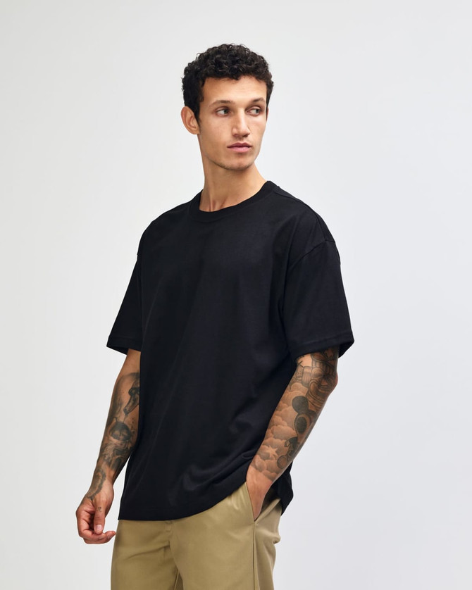 A model wearing a black American Apparel Super Heavyweight T-Shirt, paired with olive green cargo pants.