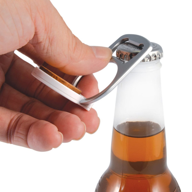 A drink bottle opener in silver, designed as a phone stand, being used to open a glass bottle.