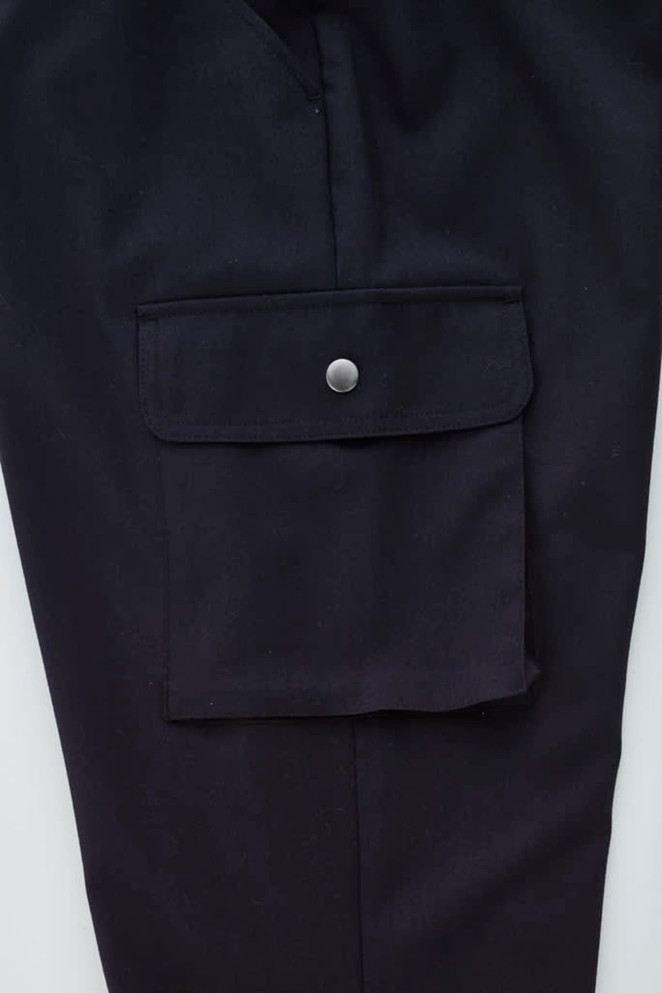 A close-up of black women's cargo pants featuring a side pocket with a button closure and a smooth fabric finish.
