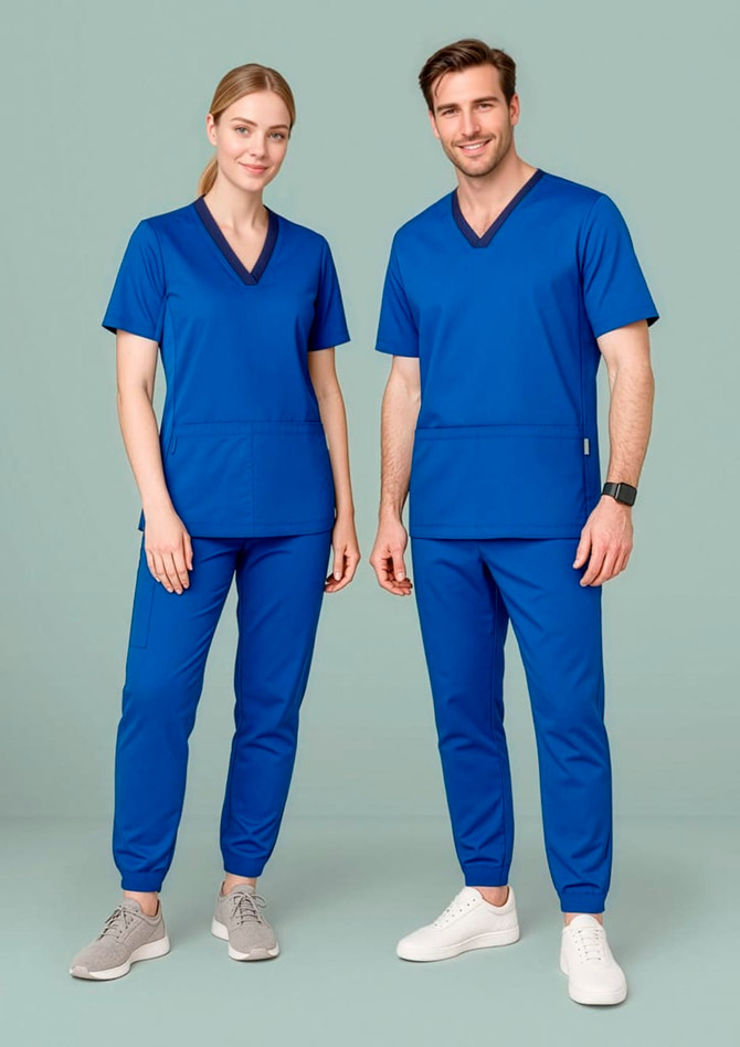A man and woman wearing blue scrub tops and slim leg jogger scrub pants, with a logo present on the apparel.