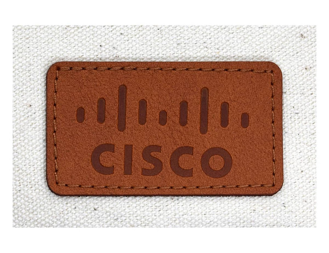 A brown leather label featuring embossed text and lines, attached to a light-coloured fabric surface.