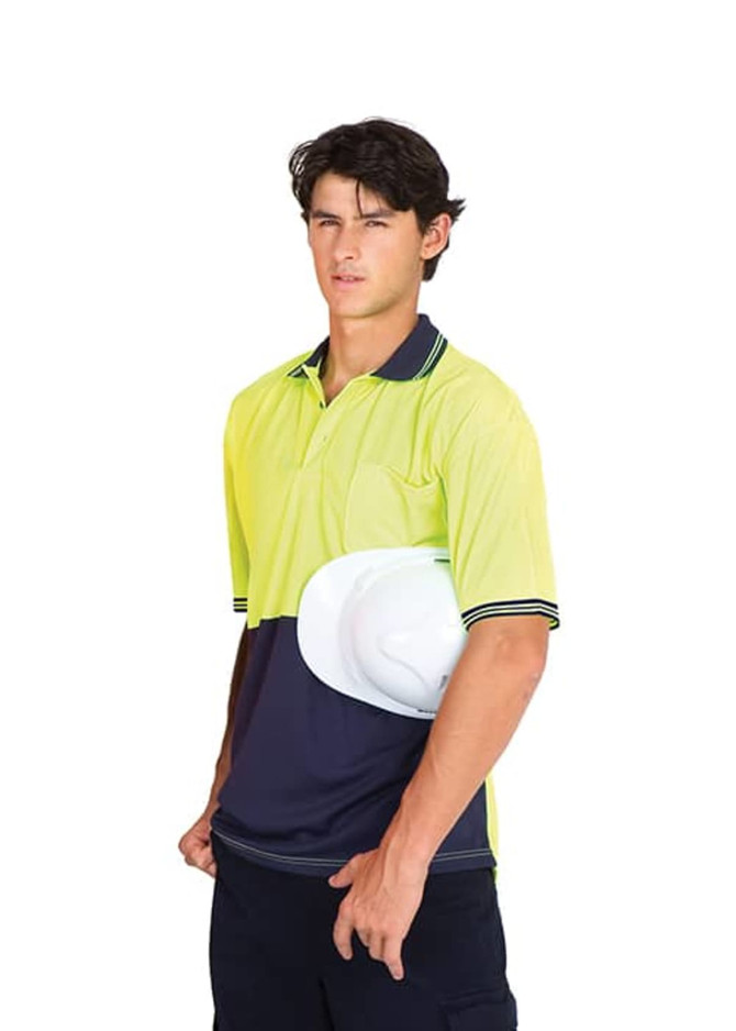 A high visibility polo shirt in bright yellow and navy blue, featuring a branded logo, held by a model wearing work pants.