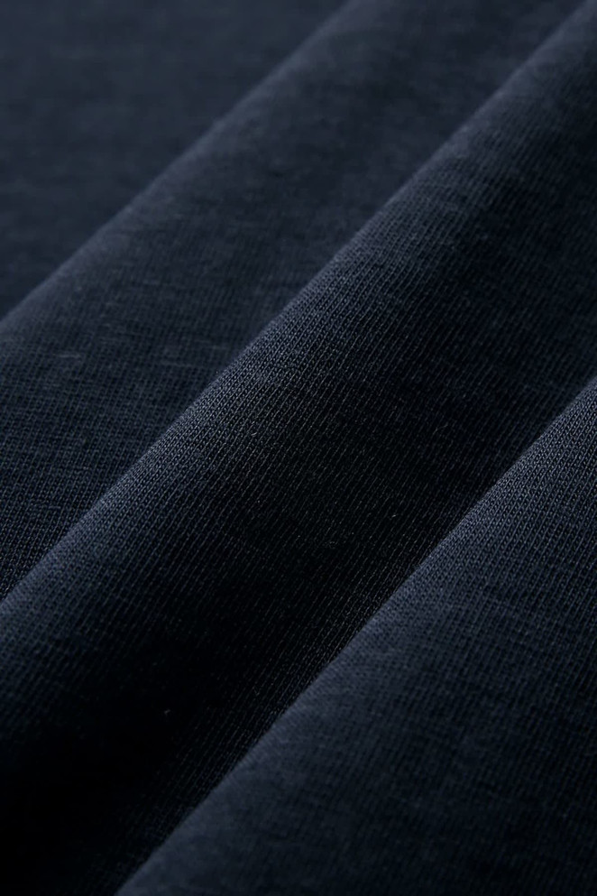 A close-up of dark navy combed cotton fabric, showcasing soft texture and smooth finish.