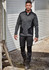 A man in dark grey and black workwear pants and a fitted grey pullover, walking in an outdoor setting.