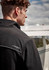 A black unisex quarter-zip polar fleece with a collar and a logo, worn by a model outdoors near an aircraft.