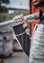 A person holding a metal pole wears a grey and black reinforced knit hoodie with a logo.
