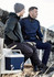 Two men seated outdoors, one wearing a grey reinforced knit hoodie and the other in a navy pullover, holding a drink bottle.