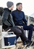 A unisex 1/2 zip pullover in navy and grey, worn by two men sitting outdoors with a drink bottle and a cooler.