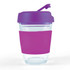 A reusable coffee cup with a clear body, purple flip lid, and a pink silicone sleeve for grip.