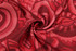 A red women's basketball uniform singlet featuring a vibrant, abstract pattern and a logo.