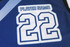 A blue basketball singlet featuring a large white number "22" and a placeholder for a player name, with a logo.