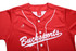 A red full button baseball tee featuring white detailing and a logo on the upper left side.