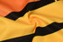 A close-up of a fabric featuring orange and yellow with black stripes, showcasing a textured design.