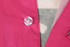 A close-up of a pink beach shirt with a button detail and part of a patterned fabric visible underneath.